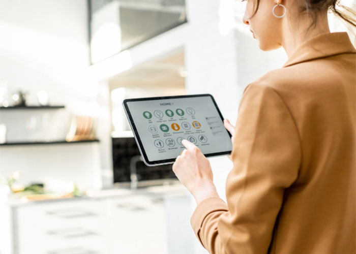 Zenska oseba s tablico v roki upravlja pametno hiso.